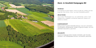 Luftaufnahme einer Rasenfläche mit eingemähtem Minos‑Logo.