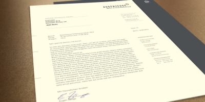 Mockup eines Briefbogens auf cremeweißem Papier mit dem Augenzeuge-Logo. Daneben die dunkelgraue Rückseite mit weißem Slogan und QR-Code auf einem braunen Hintergrund.