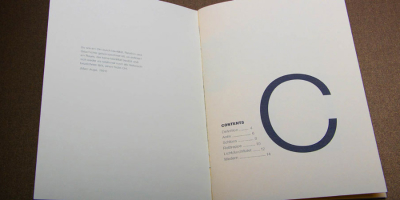 Aufgeschlagene Broschüre: Die linke Seite zeigt ein kurzes einleitendes Zitat von Marc Augé. Rechts dominiert ein riesiges, dunkelblaues ‚C‘ als Initiale für das Inhaltsverzeichnis (Contents), das schlicht darunter gelistet ist.