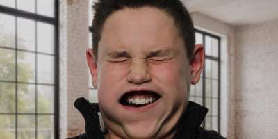 Eine Person in einem hellen Raum, deren Gesicht durch kräftige Luftbewegung stark verzogen ist, mit geschlossenen Augen und aufgeblähten Wangen.